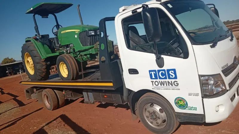 Tractor transported on rollback tow truck